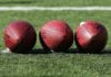 The NFL and Brazil Football Brasileiro - Three footballs lined up on grass field.