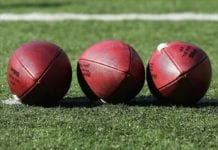 Football Brasileiro - Three footballs lined up on grass field.