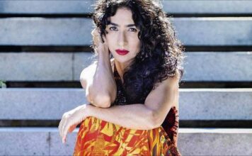 Marisa Monte's 10 favorite Brazilian songs: The Brazilian music star poses in a orange and yellow flame dress againsta wooden background