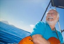 Brazilian musician Roberto Menescal holding guitar in boat