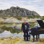 Brazilian pianist Ricardo Bacelar standing nest to grand paino in Ceara Brazil