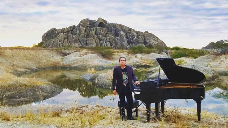 Brazilian pianist Ricardo Bacelar standing nest to grand paino in Ceara Brazil
