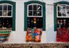 Experience Brazil’s World Heritage Sites. Colorful handmade rugs drape from open windows from the outside of a home in Ouro Preto Brazil.
