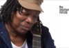 Milton Nascimento's Milestone Year. Nascimento wears his trademak tan cap while holding his guitar.