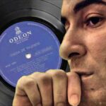 A world without Bossa Nova. Brazilian singer Joao Gilberto in profile with his debut record album in the background