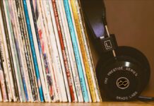 Record collection of 12 Influential Brazilian Jazz Albums on a wood shelf with black headphones leansing against them.