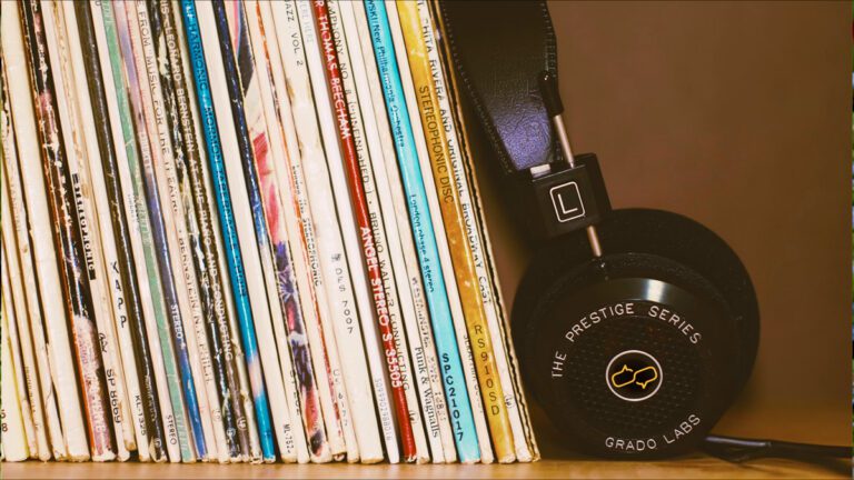 Record collection of 12 Influential Brazilian Jazz Albums on a wood shelf with black headphones leansing against them.